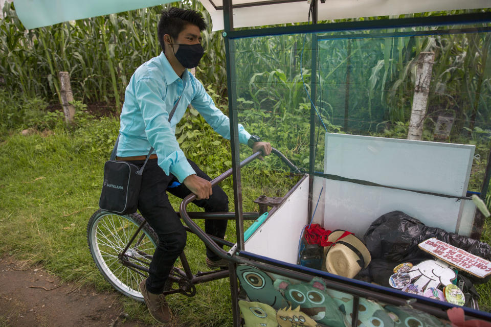 Teacher Gerardo Ixcoy pedals his adult tricycle converted into a mobile classroom past cornfields, in Santa Cruz del Quiche, Guatemala, Wednesday, July 15, 2020. When the novel coronavirus closed Guatemala's schools in mid-March, the 27-year-old invested his savings in the classroom-on-a-trike in order to give individual instruction to his sixth-grade students. (AP Photo/Moises Castillo)