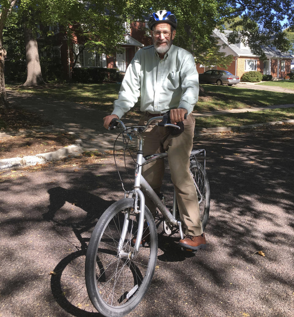 In this Oct. 17, 2018 photo provided by Marjorie Sable, George Smith, professor emeritus at the University of Missouri who won the 2018 Nobel Prize for chemistry. rides his bike on a biking/walking trail in Columbia, Mo. The university is honoring its Nobel Prize-winning scientist with an unusual accolade: a dedicated bicycle rack slot. It will be a standard bike rack, the same as those used by other bicyclists on campus. But the university plans to post a sign letting everyone know that this particular space belongs to a Nobel laureate. (Marjorie Sable photo via AP)