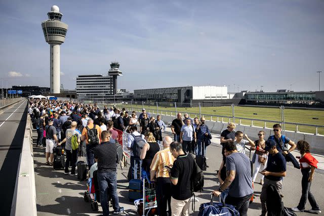 <p>AFP/Getty Images</p> Travelers queue at Schiphol Airport in Amsterdam.