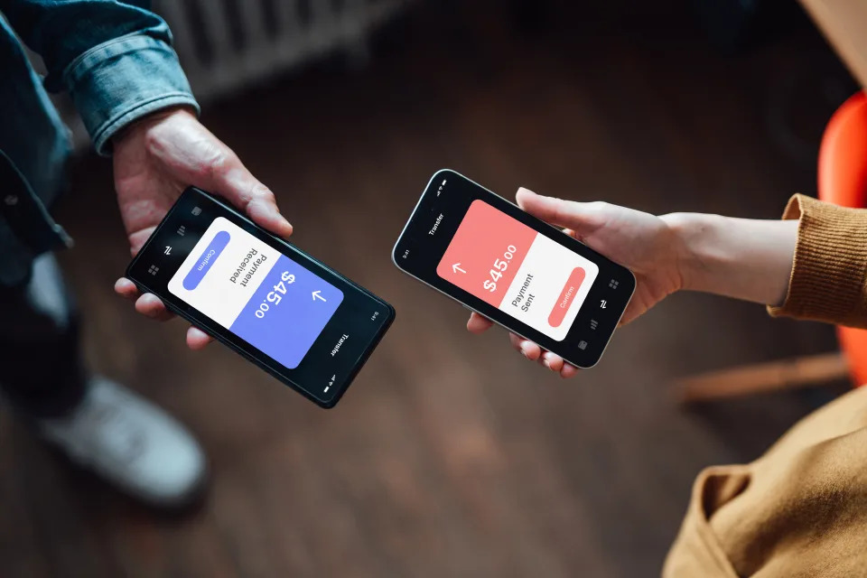 High angle view of two hands holding smart phone, transferring money via mobile banking app. Mockup image of two hands using smart phone.