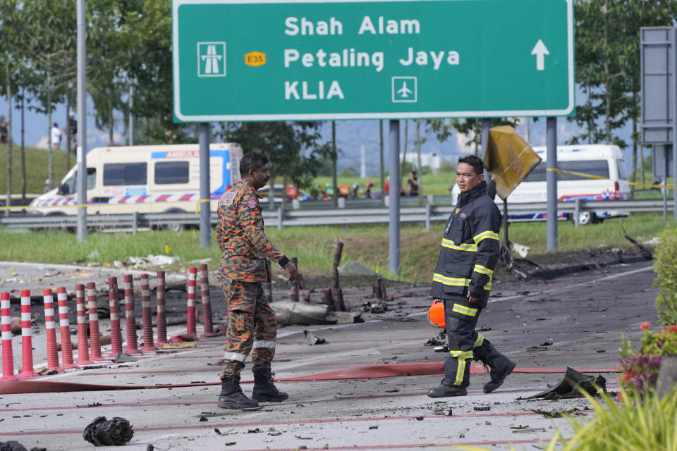 Members of the fire and rescue department inspect the crash site of a small plane in Shah Alam district, Malaysia, Thursday, Aug. 17, 2023. Police say a small aircraft has crashed in the suburb of Malaysia's central Selangor state, with multiple bodies recovered. (AP Photo/Vincent Thian)