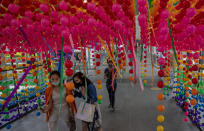 Shoppers walk through decorations at the entrance to a shopping mall promoting a sale Thursday, Aug. 6, 2020, in Bangkok, Thailand. Thailand has managed to curb COVID-19 infections over the last three months with strict controls on entry into the country and aggressive testing and quarantine requirements. But its economy is expected to contract by at least 5% in 2020, according to the World Bank. (AP Photo/ Gemunu Amarasinghe)