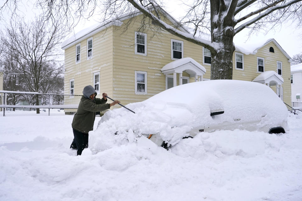 A man brushes snow off his car, Tuesday, Feb. 2, 2021, in Lawrence, Mass. A sprawling, lumbering winter storm has walloped the Eastern U.S., shutting down coronavirus vaccination sites, closing schools and halting transit. (AP Photo/Elise Amendola)