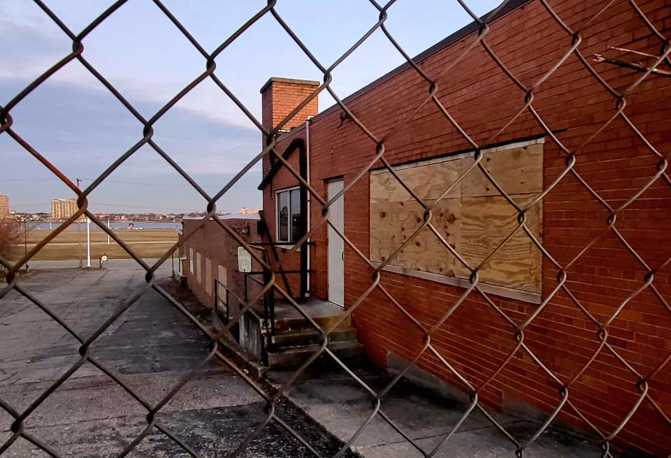 A boarded-up window is shown at the old Port Huron post office, 1300 Military St., late in the afternoon of Thursday, Dec. 14, 2023, through a fence set up along the sidewalk prior to the building's demolition.
