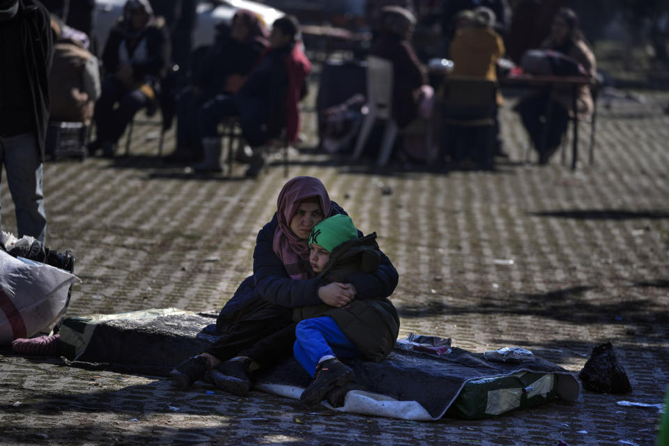 A woman hugs her son as they and others sit in a public garden in Adiyaman, southern Turkey, Sunday, Feb. 12, 2023. Six days after earthquakes in Syria and Turkey killed tens of thousands, sorrow and disbelief are turning to anger and tension over a sense that there has been an ineffective, unfair and disproportionate response to the historic disaster. (AP Photo/Khalil Hamra)