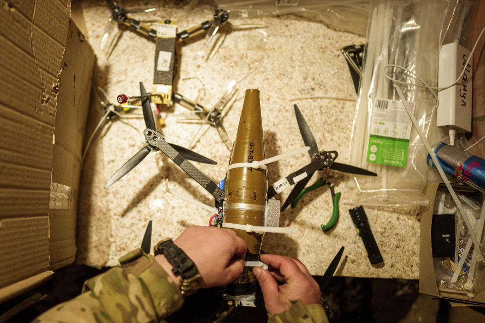 A Ukrainian serviceman of the ACHILLES battalion of the 92nd brigade attaches ammunition to a suicide drone before a flight over Russian positions in the Kharkiv region of Ukraine on Sunday, May 12, 2024. (AP Photo/Evgeniy Maloletka)