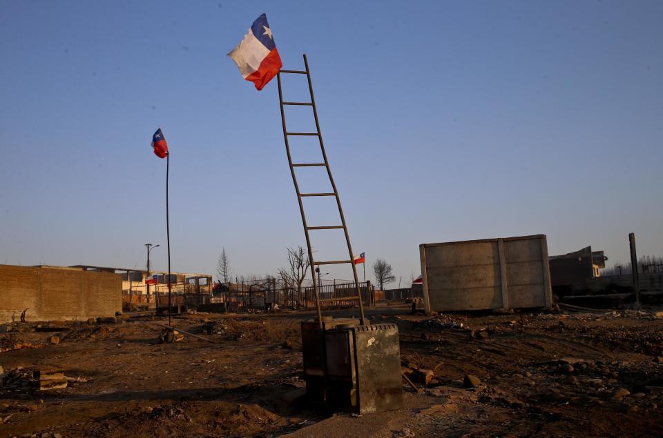 National flags fly over the scorched landscape of Chile's Santa Olga community, Tuesday, Jan. 31, 2017. The national forestry agency says Chile's raging wildfires have destroyed nearly 904,000 acres (366,000 hectares) since Jan. 15. (AP Photo/Esteban Felix)