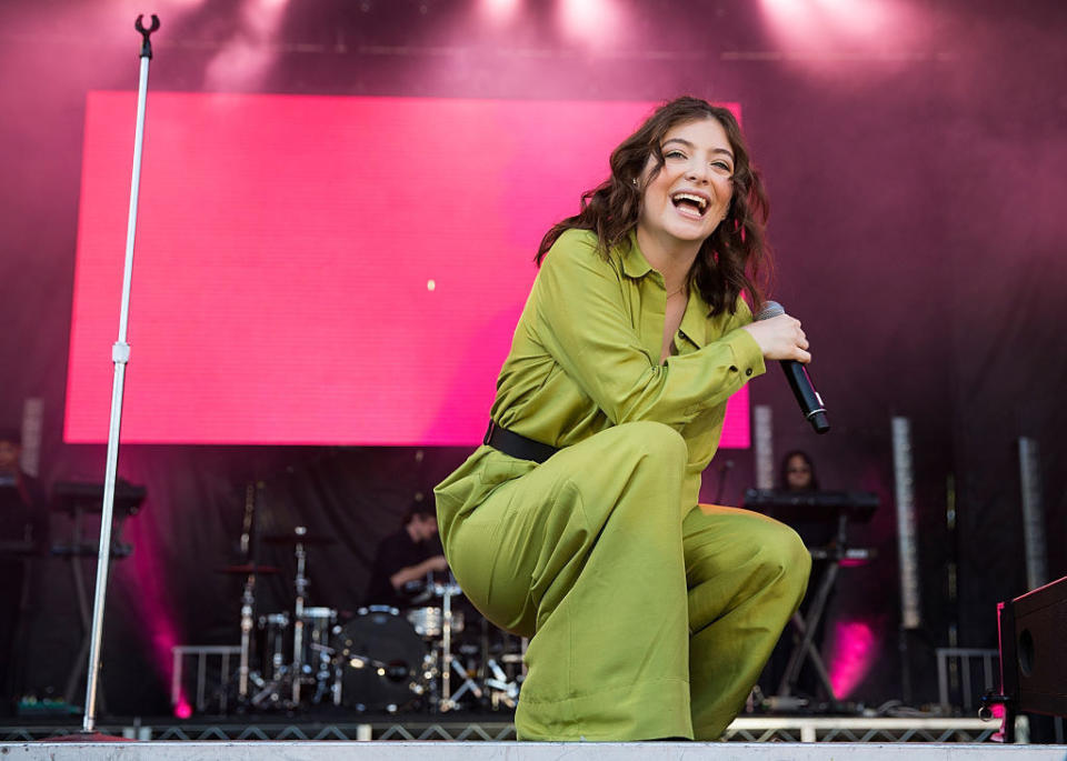 Photo of Lorde performing live in a green jumpsuit