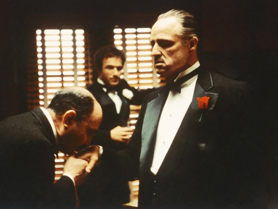 A man kissing Don Vito Corleone's hand.