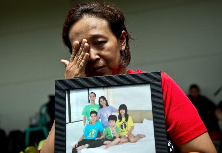 An Indonesian woman wipes her eyes while holding a family picture of passengers on the missing AirAsia plane, outside the crisis-centre set up at Juanda International Airport in Surabaya