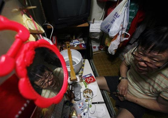 A man sits inside his "cubicle" home, one of the 19 24-square feet units inside a 600 square foot residential apartment complex in Hong Kong September 16, 2009. The Hong Kong government estimates that about 100,000 people live in similar "cubicle" units, which cost an average monthly rental rate of $150, in one of the world's largest financial hubs, according to the Society for Community Organization, an NGO which helps those in need.