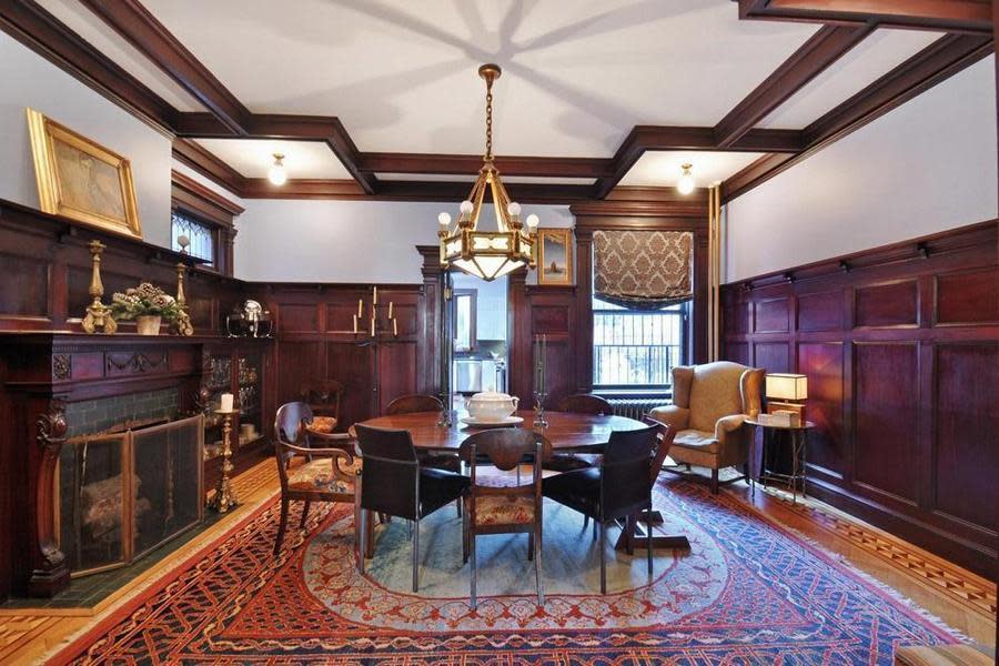 <p>The dining room boasts mahogany panels, high ceilings and a fireplace. In total, the home has six fireplaces. (Zillow) </p>