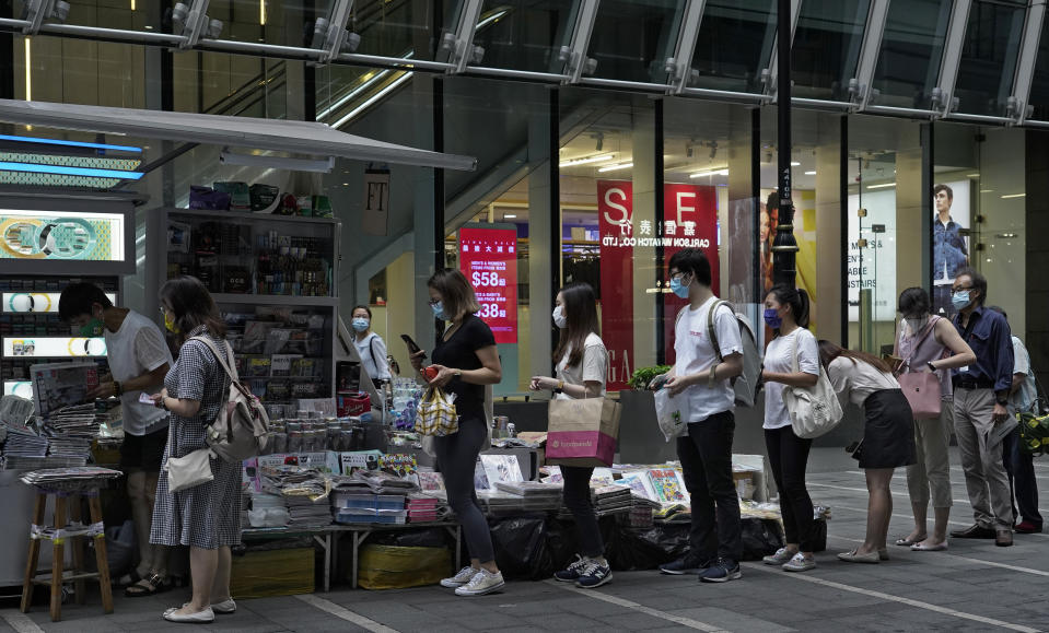 People queue up at a news stand to buy copies of Apple Daily at a downtown street in Hong Kong Tuesday, Aug. 11, 2020, as a show of support, a day after the arrest of its founder Jimmy Lai. Hong Kong authorities arrested media tycoon Jimmy Lai on Monday, broadening their enforcement of a new national security law and stoking fears of a crackdown on the semi-autonomous region's free press.(AP Photo/Vincent Yu)