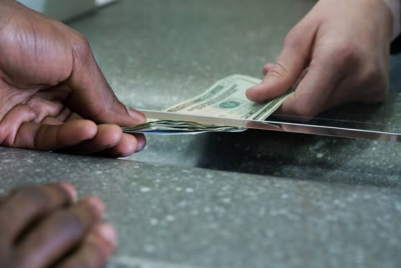 Cash being passed through a bank teller window
