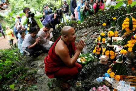 A Buddhist monk and relatives pray near Tham Luang caves during a search for 12 members of an under-16 soccer team and their coach, in the northern province of Chiang Rai, Thailand, June 27, 2018. REUTERS/Soe Zeya Tun