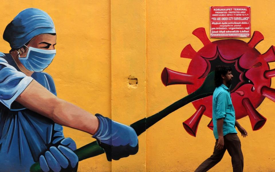 A man walks past a Covid-19 coronavirus awareness mural along the roadside in Chennai