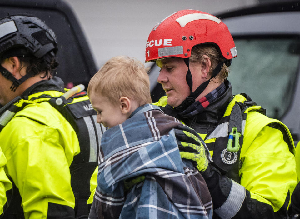 A firefighter helps a young resident out of a raft after evacuating residents at Creekwood Apartments due to flooding on Thursday, Nov. 12, 2020 in Winston-Salem, N.C. (Andrew Dye/The Winston-Salem Journal via AP)