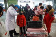 A medical official takes the body temperature of a child at the departure hall of the airport in Changsha