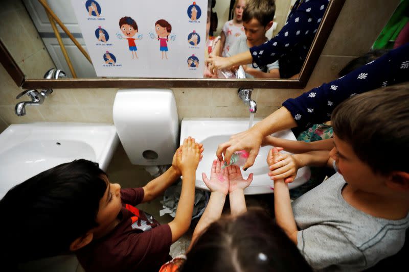 Teacher shows children how to wash their hands at her kindergarten in Jerusalem