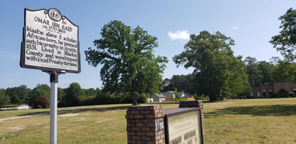 A North Carolina historical marker on Murchison Road in Fayetteville, NC, marks the life of Omar Ibn Said, who is the namesake for the mosque pictured in the background.