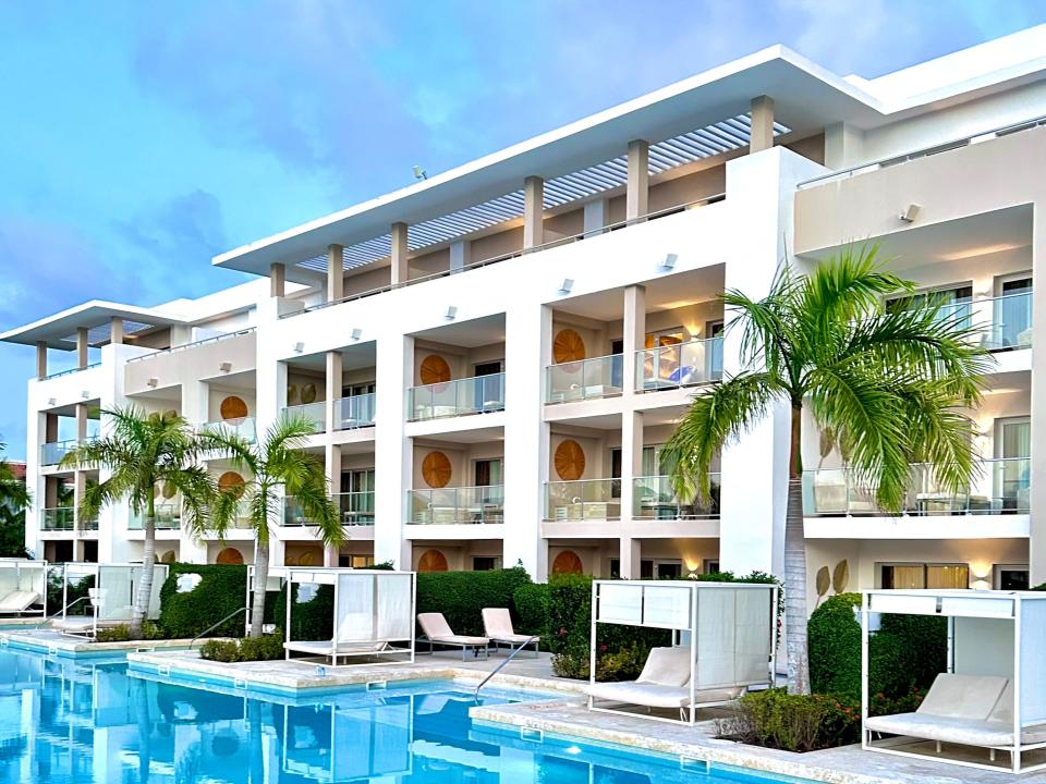 hotel with blue water and palm trees in front of it