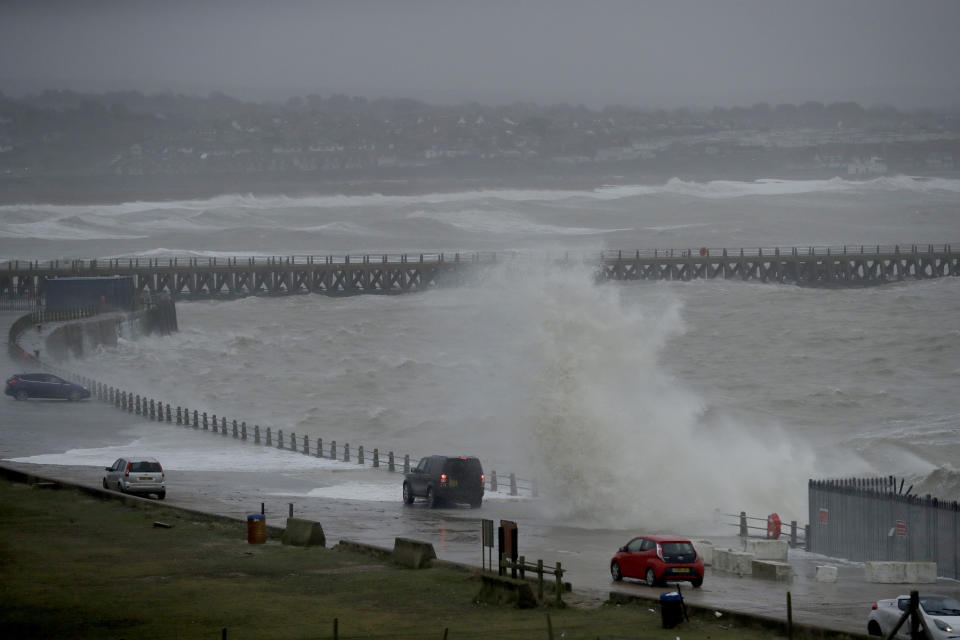 A wave crashes over the sea wall as cars slowly pass, as Storm Ciara hits Newhaven, on the south coast of England, Sunday, Feb. 9, 2020. Trains, flights and ferries have been cancelled and weather warnings issued across the United Kingdom and in northern Europe as the storm with winds expected to reach hurricane levels batters the region. (AP Photo/Matt Dunham)