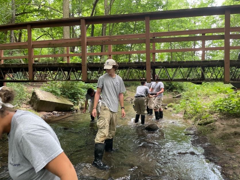 Working around one of the aging foot bridges, AmeriCorps members clean up Eller Ditch at The Mishawaka Res in July 2023.