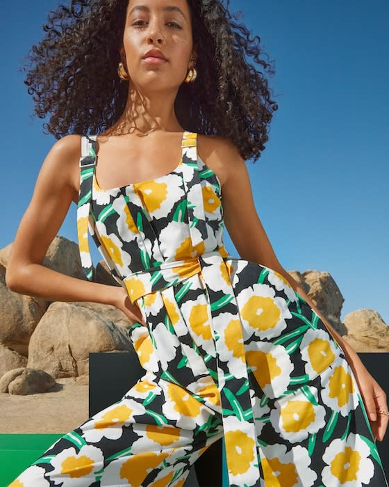 A woman wearing a sleeveless jumpsuit in a bright floral print.