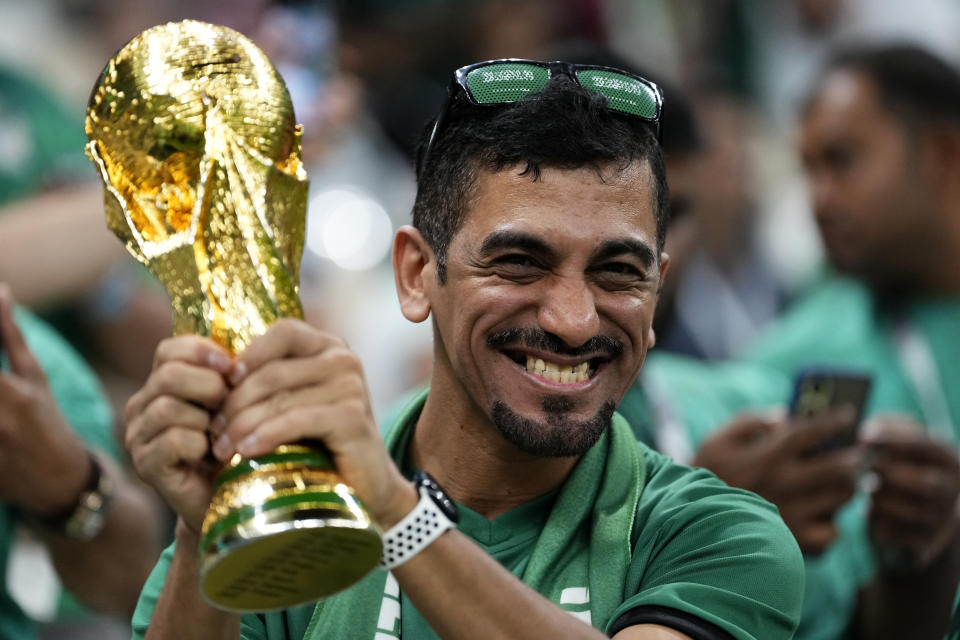 A fan smiles holding a World Cup trophy replica prior the group C soccer match between Saudi Arabia and Mexico, at the Lusail Stadium in Lusail, Qatar, Wednesday, Nov. 30, 2022. (AP Photo/Manu Fernandez)