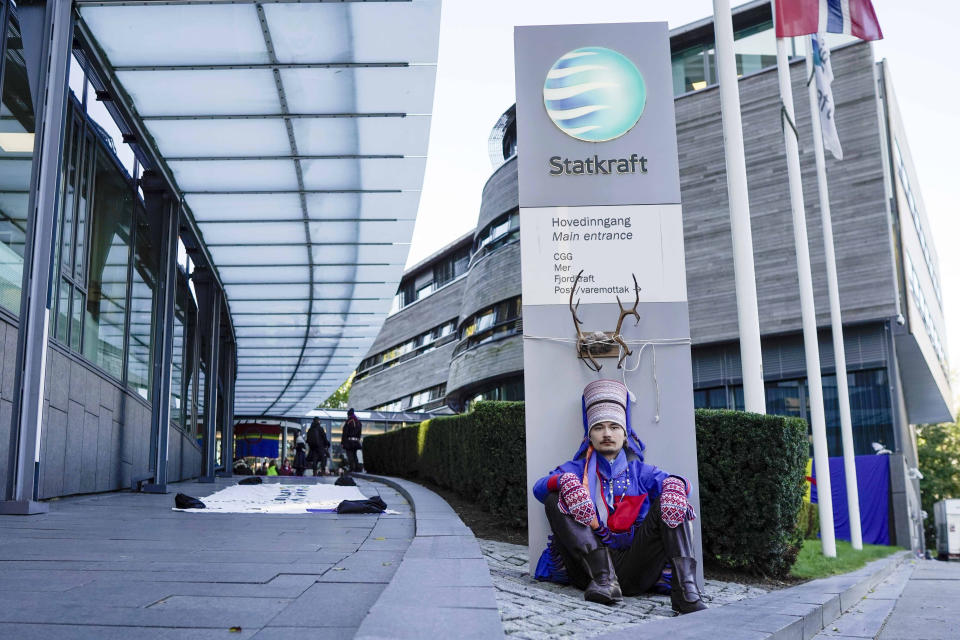 Activist Mihkkal Hætta wears a traditional Sami outfit as he sits in protest outside the entrance of Statkraft, a state-owned company that operates 80 of the wind turbines at Fosen, in central Norway’s Fosen district, about 450 kilometers (280 miles) north of the capital of Oslo, in Oslo, Thursday, Oct. 12, 2023. Dozens of activists in Norway on Thursday blocked the entrance to one of the main operators of a wind farm they say hinders the rights of the Sami Indigenous people to raise reindeer. (Cornelius Poppe/NTB Scanpix via AP)