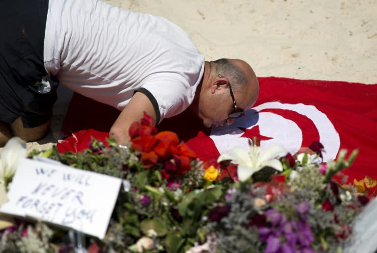 A man kisses a Tunisian flag at the site of a shooting attack on the beach in front of the Riu Imperial Marhaba Hotel in Port el Kantaoui, on the outskirts of Sousse south of the capital Tunis, on June 28, 2015. The Islamic State (IS) group claimed responsibility on June 27 for the massacre in the seaside resort that killed nearly 40 people, most of them British tourists, in the worst attack in the country's recent history. AFP PHOTO / KENZO TRIBOUILLARD