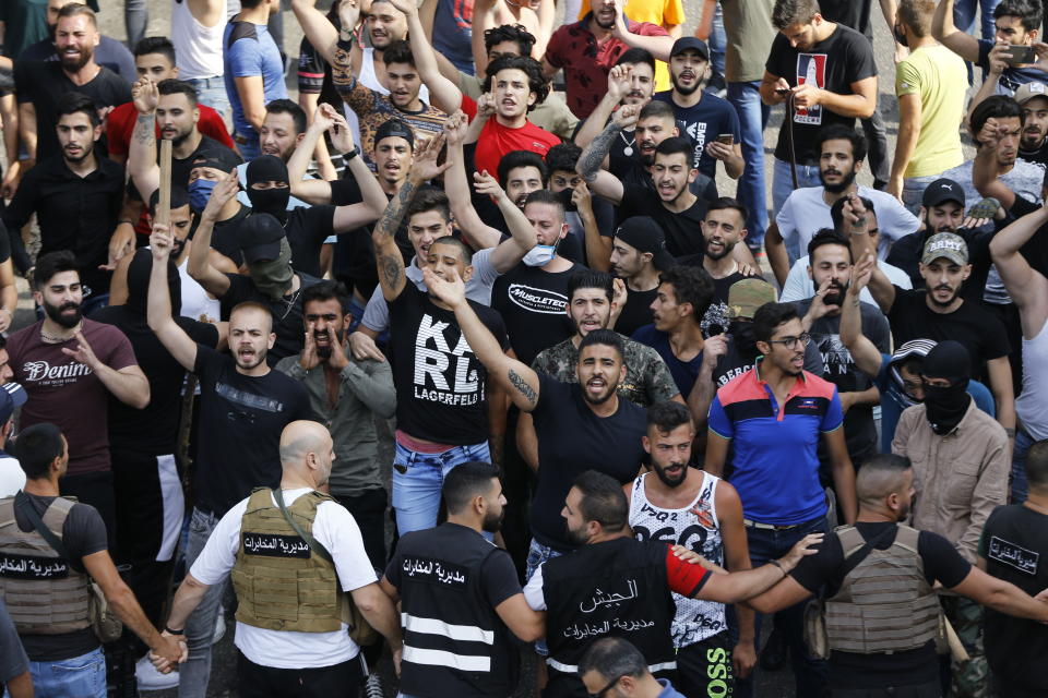 Shiite Hezbollah and Amal Movement groups stand in front of Lebanese army, foreground, as they shout slogans against anti-government protesters, in downtown Beirut, Lebanon, Saturday, June 6, 2020. Hundreds of Lebanese demonstrators gathered in central Beirut Saturday, hoping to reboot nationwide anti-government protests that began late last year amid an unprecedented economic and financial crisis. (AP Photo/Bilal Hussein)