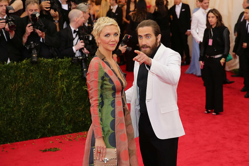 Two celebrities posing on the red carpet, the man in a suit, the woman in a patterned dress