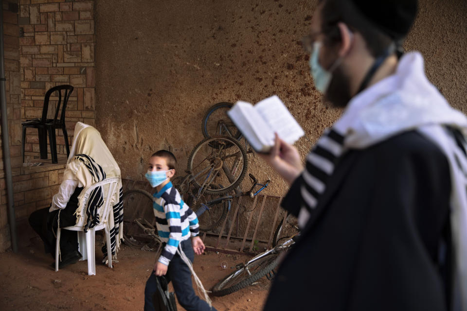 Judíos ultraortodoxos durante una plegaria matinal junto a su casa, ya que las sinagogas han limitado el aforo dentro de las medidas del gobierno para frenar los contagios de coronavirus en Bnei Brak, Israel, el jueves 9 de julio de 2020. (AP Foto/Oded Balilty)