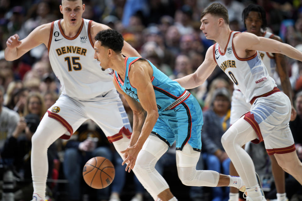 Phoenix Suns guard Landry Shamet, front, chases down a loose ball as Denver Nuggets center Nikola Jokic, back left, and guard Christian Braun defend in the first half of an NBA basketball game, Sunday, Dec. 25, 2022, in Denver. (AP Photo/David Zalubowski)