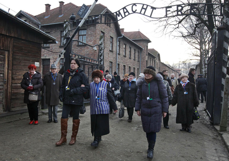 File-In this file photo taken Jan. 27, 2016 Holocaust survivors walk with others through the main gate of the former Nazi German Auschwitz-Birkenau death camp in Oswiecim, Poland. The camp's museum is objecting to a scene in the Amazon series "Hunters" that shows a game of murderous human chess, saying such a game never took place there. (AP Photo/Czarek Sokolowski)