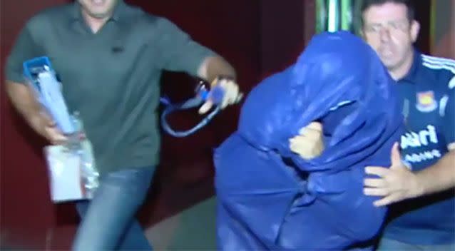 Vincenzo Mule (face covered in blue outfit) was rushed past media following his arrest. Source: 7 News