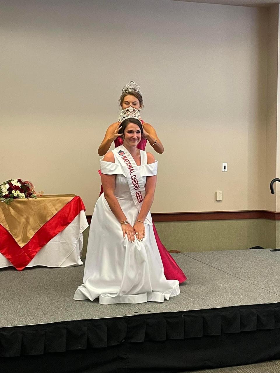 Reigning National Cherry Queen Olivia Coolman, of Traverse City, accepts her crown in 2022 from previous queen Allie Graziano. On Monday, Coolman is scheduled to become the first queen to attend the Wiigwaasmin Pageant, the final piece of the annual Native American powwow at the National Cherry Festival.