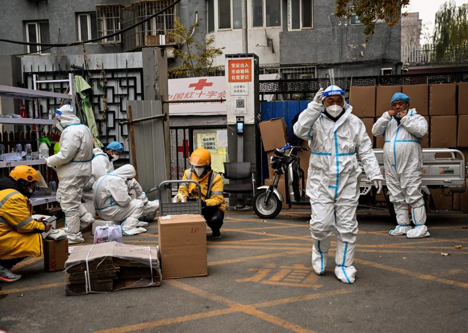Health workers guard the entrance of a residential area under lockdown due to Covid-19 coronavirus restrictions in Beijing  (AFP via Getty Images)