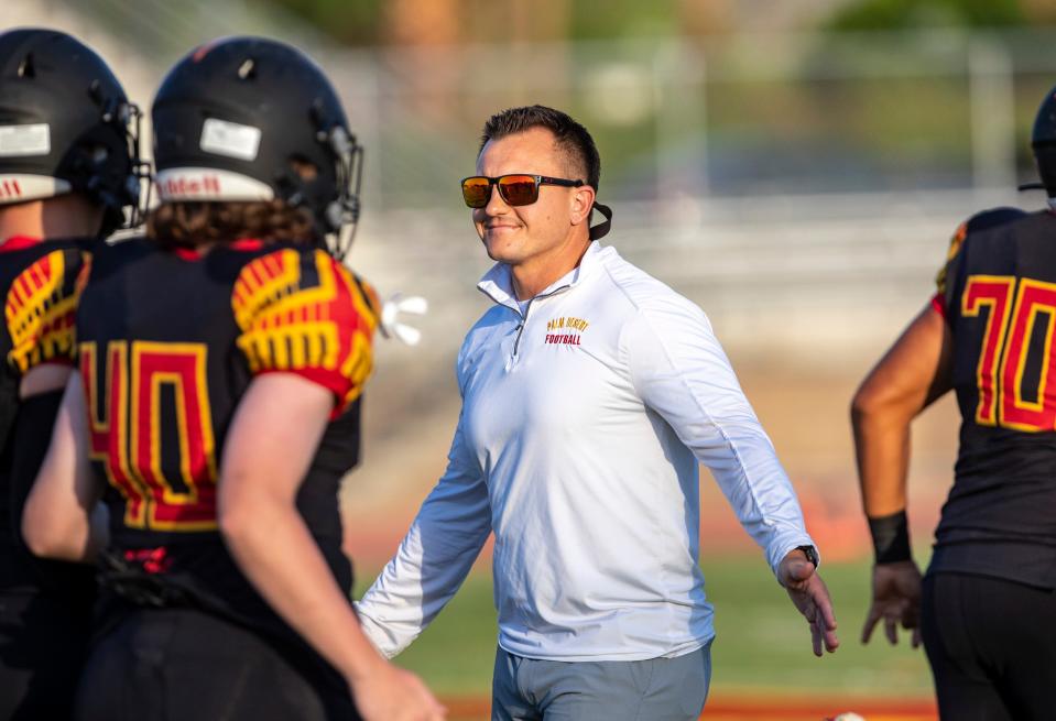 Palm Desert head coach Shane McComb high-fives players as they take the field for warm-ups before their game at Palm Desert High School in Palm Desert, Calif., Thursday, Aug. 18, 2022. 