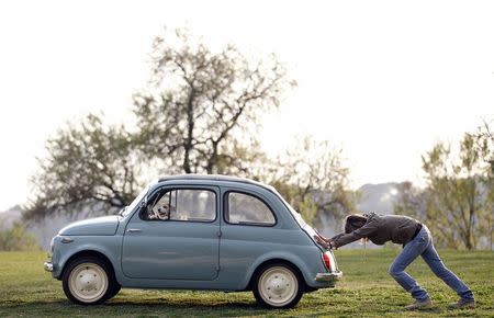 A woman pushes her Fiat 500 car as her dog sits inside, in a neighbourhood of Rome in this March 23, 2012 file photo. REUTERS/Alessandro Bianchi/Files