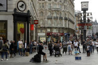 People listen to an entertainer perform in Leicester Square, central London, Saturday, Sept. 19, 2020. Fresh nationwide lockdown restrictions in England appear to be on the cards soon as the British government targeted more areas Friday in an attempt to suppress a sharp spike in new coronavirus infections. (AP Photo/Matt Dunham)