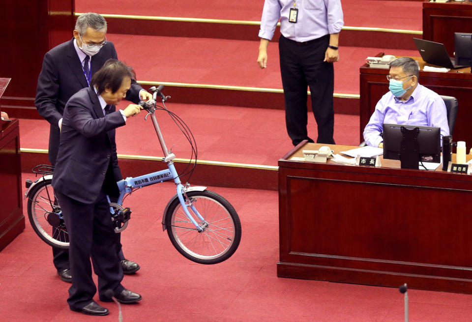 市議員王世堅（左下）2021年4月在議會痛斥市長柯文哲（右）假藉推廣自行車之名行銷自己，並致贈貼有「政治不難 找回網軍而已」字樣的腳踏車給柯。（資料照/范揚光攝）