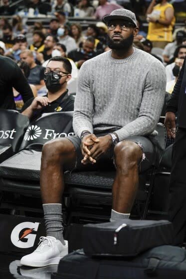 Lakers forward LeBron James sits on the bench in street clothes during a game against the San Antonio Spurs