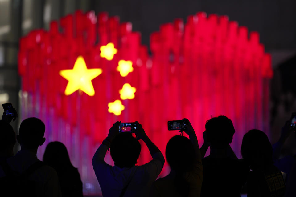 Visitors take photos with their smart phones of an installation depicting a heart shape Chinese national flag in Shanghai, China, Friday, Sept. 27, 2019. China will mark its 70th anniversary on Oct. 1, 2019. (AP Photo)