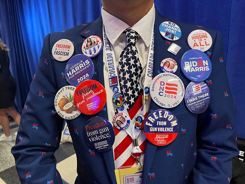 First-time Colorado delegate Kenny Vann Nguyen of Broomfield, Colo. wears a jacket embroaidered with Democratic donkey icons and pins with campaign messages during the final day of the Democratic National Convention at the United Center.