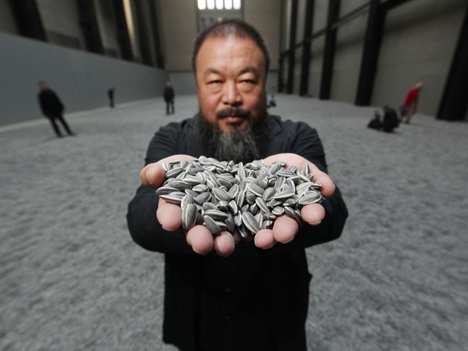 Ai Weiwei holds some seeds from his Unilever installation Sunflower Seeds at Tate Modern, October 2010Getty