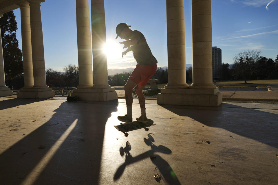Drew Darnell rides his skateboard at Cheesman Park Pavilion on Wednesday, Dec. 1, 2021, in Denver. The city is close to breaking a record for its longest streak ever without snow. (AP Photo/Brittany Peterson)