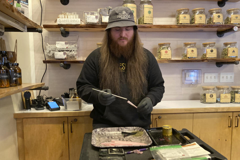 River Herber, an employee of Preserve Oregon, a marijuana shop in Salem, Oregon, rolls a joint on Jan. 31, 2023. Along the West Coast, which has dominated U.S. marijuana production from long before legalization, producers are struggling with what many call the failed economics of legal pot...a challenge inherent in regulating a product that remains illegal under federal law. (AP Photo/Andrew Selsky)