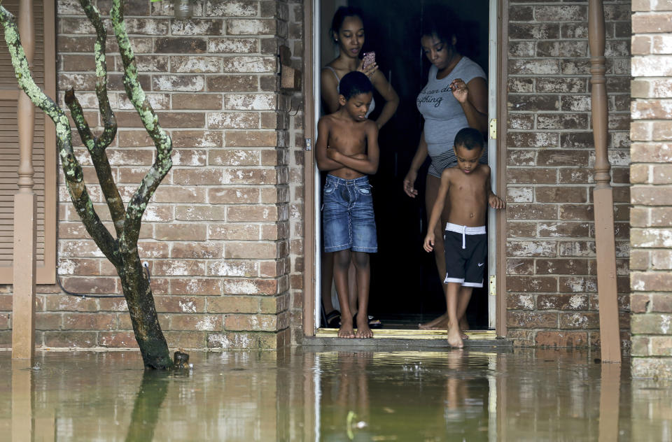 Eight-year-old Cam'ron Maltie, left, and Adrian Murray, 4, look at the their flooded front lawn during Tropical Storm Beta, Tuesday, Sept. 22, 2020, in Houston. Their family has been living in the home for a year and didn't know the neighborhood flooded. (Godofredo A. Vásquez/Houston Chronicle via AP)